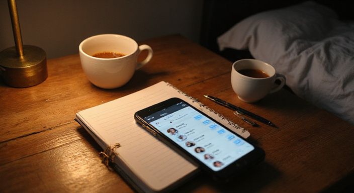 Een smartphone met een datingapp op een houten bureau.